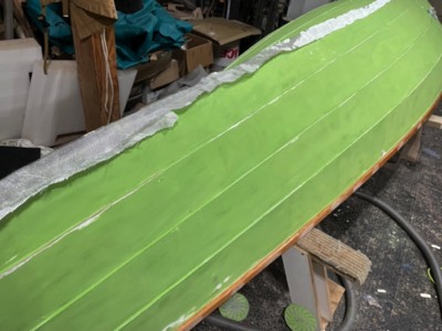  The hull is sanded and fiberglass is laid on the wood rubstrip. 